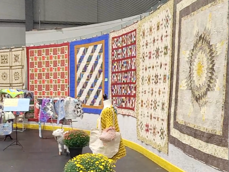 Quilts hang along the wall 